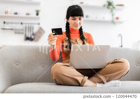 Caucasian woman shopping online using laptop and bank card at home Caucasian woman shopping online using laptop and bank card at home 120044470