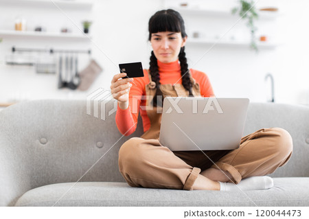Young woman shopping online using laptop and credit card at home Young woman shopping online using laptop and credit card at home 120044473