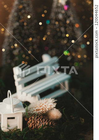 A warm, sparkling winter scene with white benches and lanterns 120044652