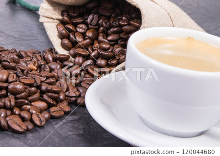White cup of coffee and roasted fragrant dark coffee grains in bag White cup of coffee and roasted fragrant dark coffee grains in bag 120044680
