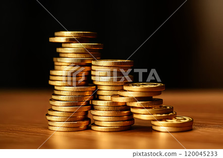 A stack of gold coins on a wooden table 120045233