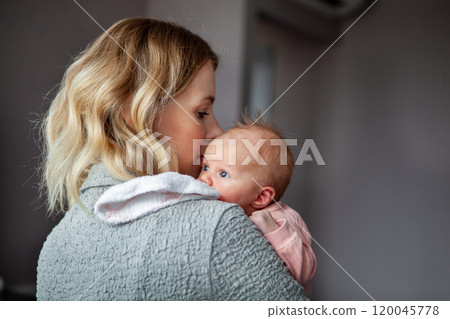 Caring mother holds small child upright while gently placing napkin on herself to keep clean, heartwarming moment of love and tenderness. Mom and newborn baby at home Caring mother holds small child upright while gently placing napkin on herself to keep clean, heartwarming moment of love and tenderness. Mom and newborn baby at home 120045778