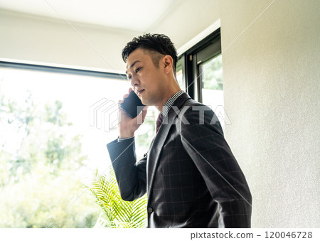 Businessman making a phone call indoors 120046728