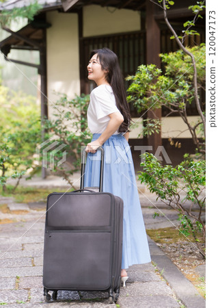 A young woman pulling a suitcase and returning to the countryside Travel image 120047173