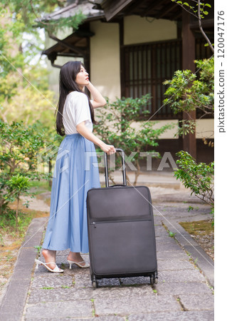 A young woman pulling a suitcase and returning to the countryside Travel image 120047176