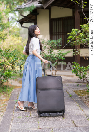 一位年輕女子背著行李箱返回鄉村的旅行形象 120047177