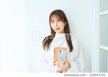 Young woman holding a notebook and smartphone Young woman holding a notebook and smartphone 120047245