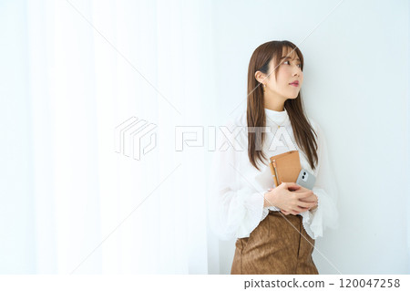 Young woman holding a notebook and smartphone Young woman holding a notebook and smartphone 120047258