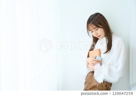 Young woman holding a notebook and smartphone Young woman holding a notebook and smartphone 120047259