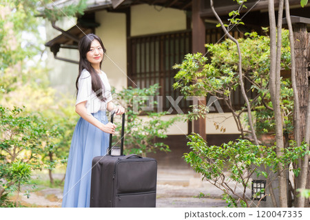A young woman pulling a suitcase and returning to the countryside Travel image 120047335