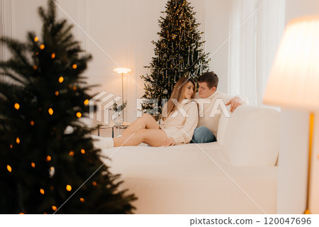 people and holidays concept - portrait of happy couple at ugly sweater party over christmas tree on background 120047696
