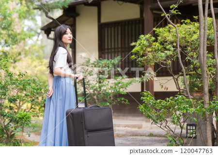 A young woman pulling a suitcase and returning to the countryside Travel image 120047763