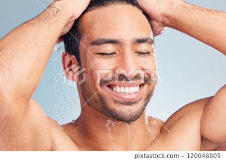 Happy man, haircare and shower for cleaning in studio, hygiene and water on blue background. Male person, grooming and soap for skincare or energy, conditioner and washing for self care or treatment 120048805