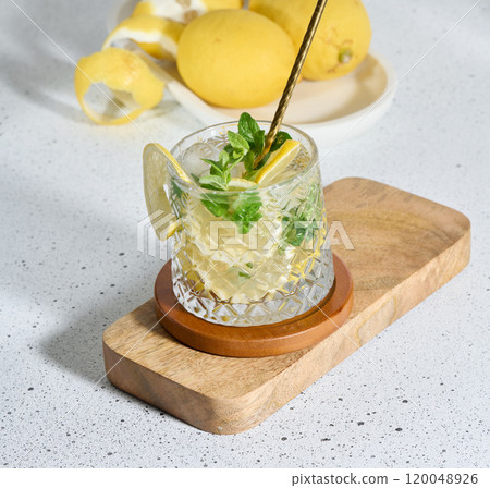Transparent glass with lemon slices, mint leaves and ice cubes on white table 120048926