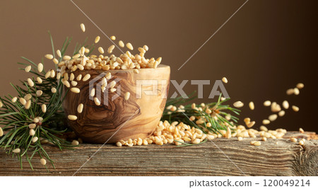 Flying peeled pine nuts on a brown background. 120049214