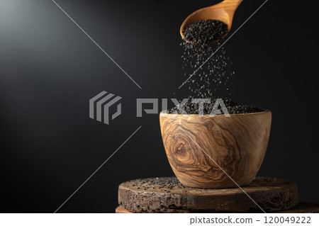 Black sesame is poured in wooden bowl. 120049222