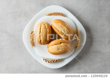 French buns and wheat ears on a marmoreal table. French buns and wheat ears on a marmoreal table. 120049229