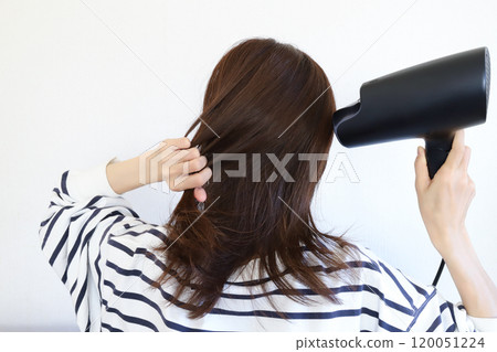 A woman drying her hair with a hair dryer A woman drying her hair with a hair dryer 120051224
