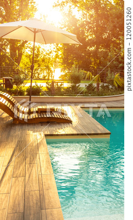 Swimming pool in modern private villa with lounge chairs, palm trees and umbrella 120051260