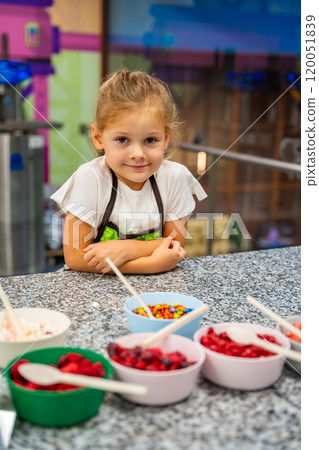 Little girl learning how to cook in a cooking class. Handmade dessert. Making chocolate candy, Child filling heart shaped mold with chocolate 120051839
