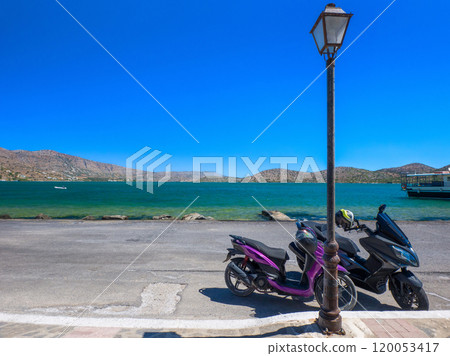 Motorbikes parked on a beach road (Elounda, Crete, Greece) 120053417