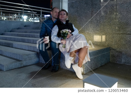 A couple sits together on a set of stairs in the city at night A couple sits together on a set of stairs in the city at night 120053460