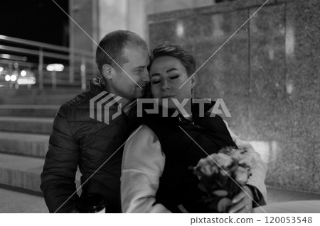 A married couple walks through the city at night, enjoying a romantic evening together 120053548