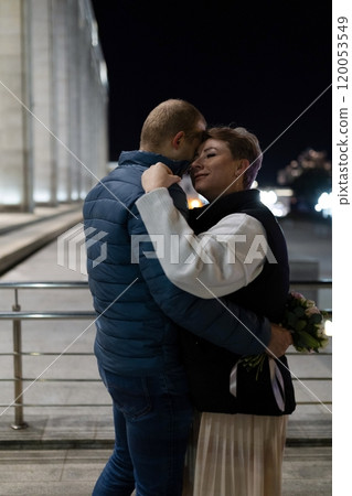 A couple embraces in the city at night, their love glowing bright in the urban landscape 120053549