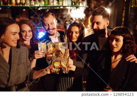 Cheering, drinking cocktails. Group of friends partying in nightclub and toasting drinks cocktails. 120054123