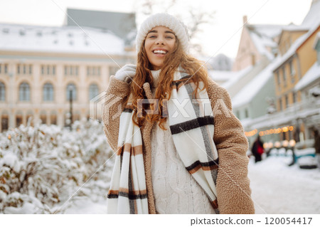 Beautiful woman playing with snow on winter street. Fashion young woman in winter park. Christmas. 120054417