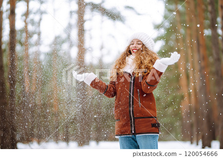 Winter smiling woman stands among snowy trees in winter forest. 120054666