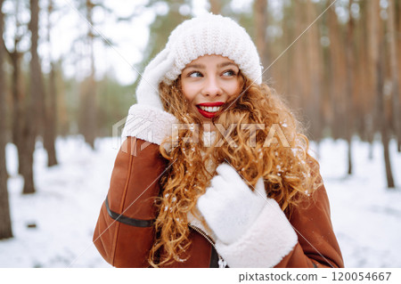 Winter smiling woman stands among snowy trees in winter forest. 120054667