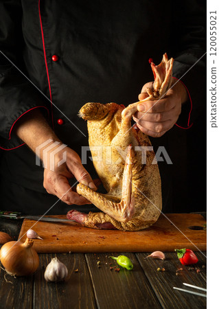 Culinary artistry in a rustic kitchen during the preparation of flavorful chicken. A skilled chef expertly prepares a whole chicken, surrounded by fresh vegetables and herbs Culinary artistry in a rustic kitchen during the preparation of flavorful chicken. A skilled chef expertly prepares a whole chicken, surrounded by fresh vegetables and herbs 120055021