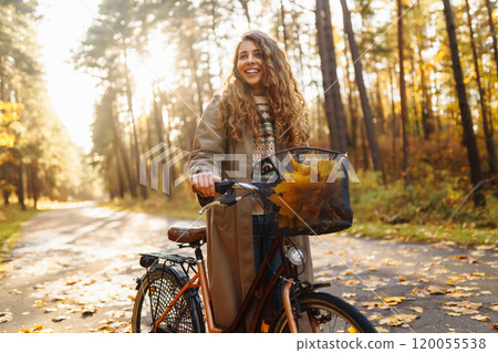 Smilling woman with bicycle enjoying autumn weather in park. Woman walking in autumn forest. Smilling woman with bicycle enjoying autumn weather in park. Woman walking in autumn forest. 120055538