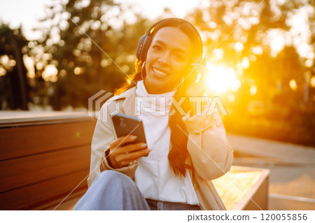 Young woman listens to music, audiobook or podcast. Communication in social networks. Lifestyle. 120055856