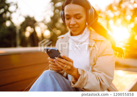 Young woman listens to music, audiobook or podcast. Communication in social networks. Lifestyle. Young woman listens to music, audiobook or podcast. Communication in social networks. Lifestyle. 120055858
