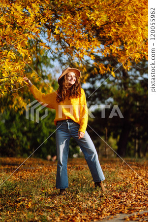 Young woman in a yellow sweater and jeans resting in nature. Fashion, style concept. People, lifestyle. 120055962