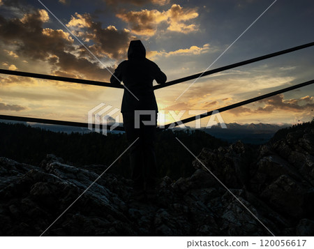 Silhouette of a female tourist admiring sunrise sky over mountain horizon Silhouette of a female tourist admiring sunrise sky over mountain horizon 120056617