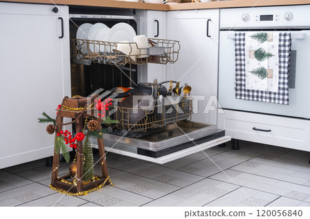 A lot of dirty dishes in the dishwasher in the festive kitchen. Helping the hostess, economy and ecology. Cleaning in the kitchen for the holidays of Christmas and New Year, after the feast and guests 120056840
