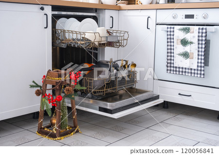 A lot of dirty dishes in the dishwasher in the festive kitchen. Helping the hostess, economy and ecology. Cleaning in the kitchen for the holidays of Christmas and New Year, after the feast and guests 120056841