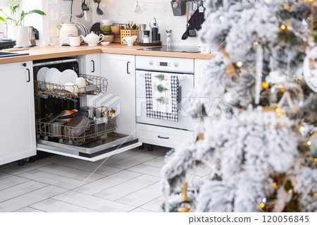 A lot of dirty dishes in the dishwasher in the festive kitchen. Helping the hostess, economy and ecology. Cleaning in the kitchen for the holidays of Christmas and New Year, after the feast and guests 120056845