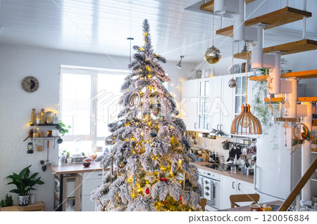 Christmas decor in white kitchen, modern village interior with a snowy Christmas tree and fairy lights. New Year, Christmas mood, cozy home, Metal modular staircase. Christmas decor in white kitchen, modern village interior with a snowy Christmas tree and fairy lights. New Year, Christmas mood, cozy home, Metal modular staircase. 120056884