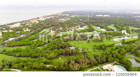 Golf course at sunset with beautiful sky and sand trap. Scenic panoramic view of golf fairway with bunker. Golf field with pines 120056904