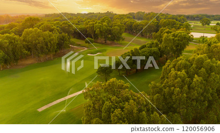 Beautiful sunset sky over a golf course during evening grass watering Beautiful sunset sky over a golf course during evening grass watering 120056906