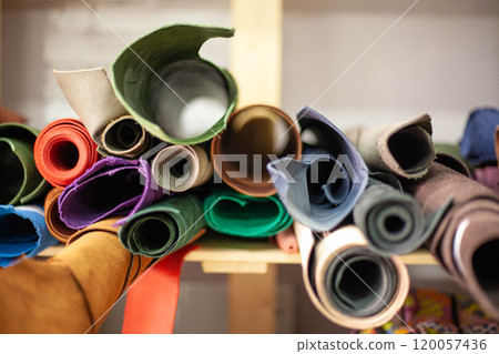 on the shelf of the leather workshop are rolls of multicolored leather for making bags purses and other leather accessories. High quality photo 120057436