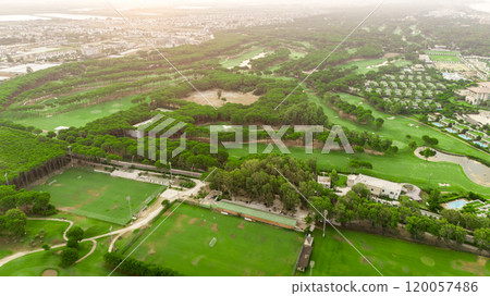 Golf course at sunset with beautiful sky and sand trap. Scenic panoramic view of golf fairway with bunker. Golf field with pines Golf course at sunset with beautiful sky and sand trap. Scenic panoramic view of golf fairway with bunker. Golf field with pines 120057486