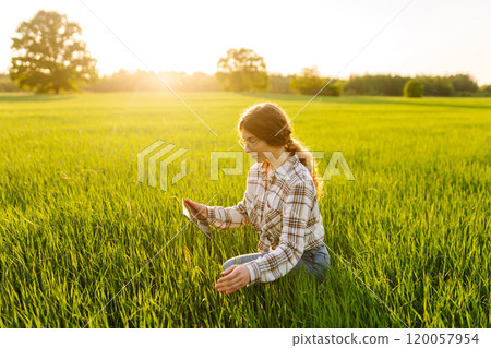Experienced woman farmer with digital tablet in hands on green wheat field. Concept of gardening. Experienced woman farmer with digital tablet in hands on green wheat field. Concept of gardening. 120057954