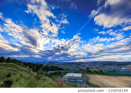 View from the ruins of Shiroyamadai Castle in Kizugawa City, the southernmost part of Kyoto Prefecture. From sunset to night view. Blue sky peeking through the clouds and the city beyond the Susukino Hills. 120058194