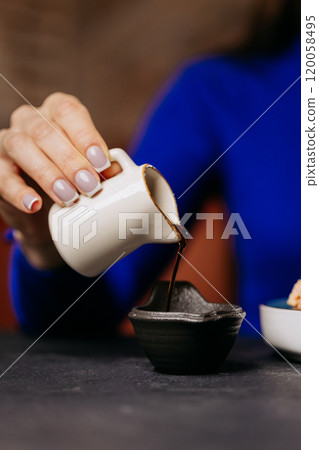 Close-up of a hand pouring soy sauce into a dipping bowl, perfect for sushi or Japanese cuisin Close-up of a hand pouring soy sauce into a dipping bowl, perfect for sushi or Japanese cuisin 120058495