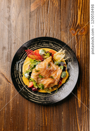 Top view of a gourmet salad with smoked salmon, vibrant greens, and artistic garnishes on table 120058498